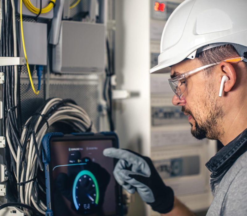 Man, an electrical technician working in a switchboard with fuses. Installation and connection of electrical equipment.
